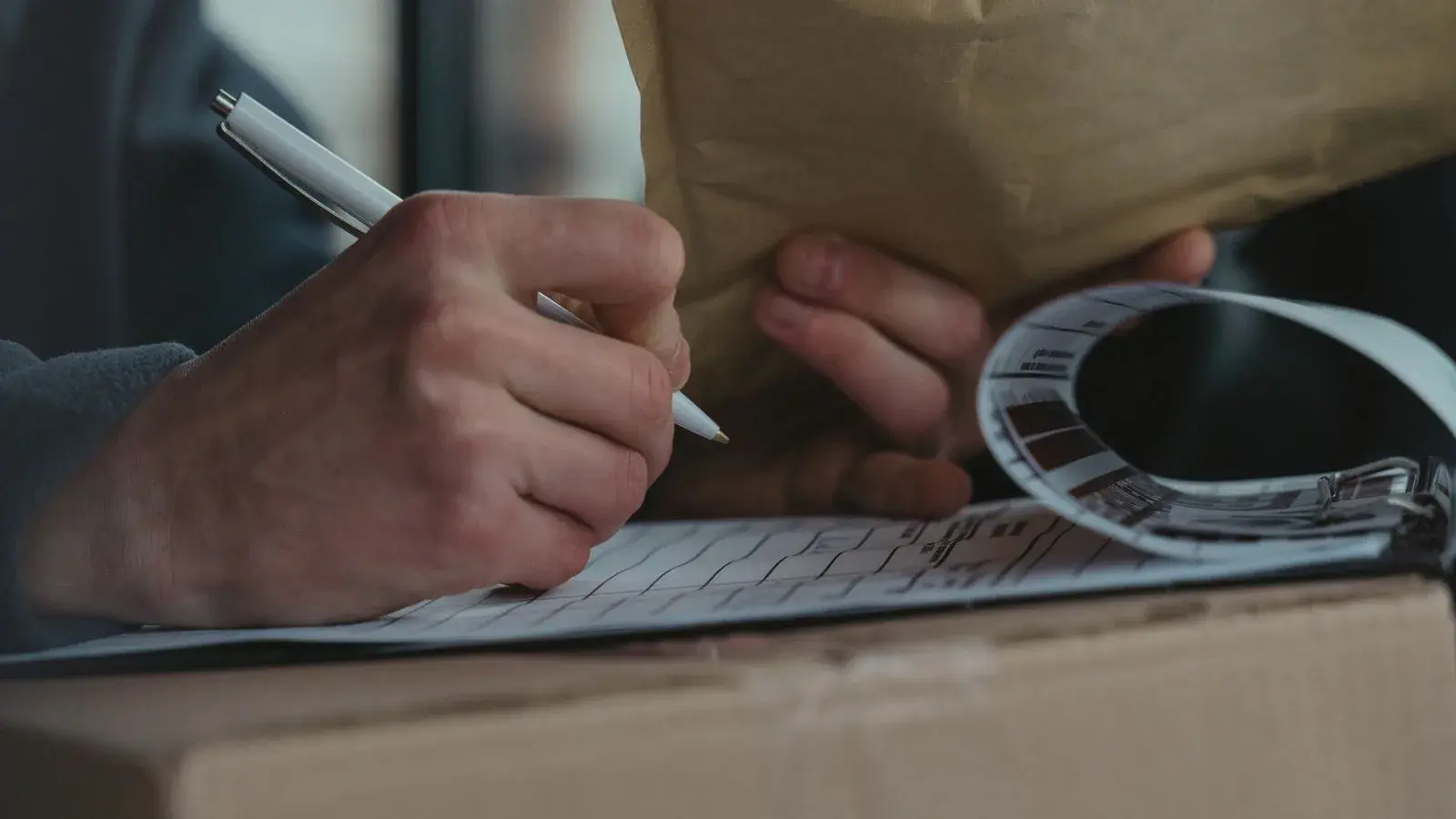 Hands checking shipping documentation against a labelled parcel