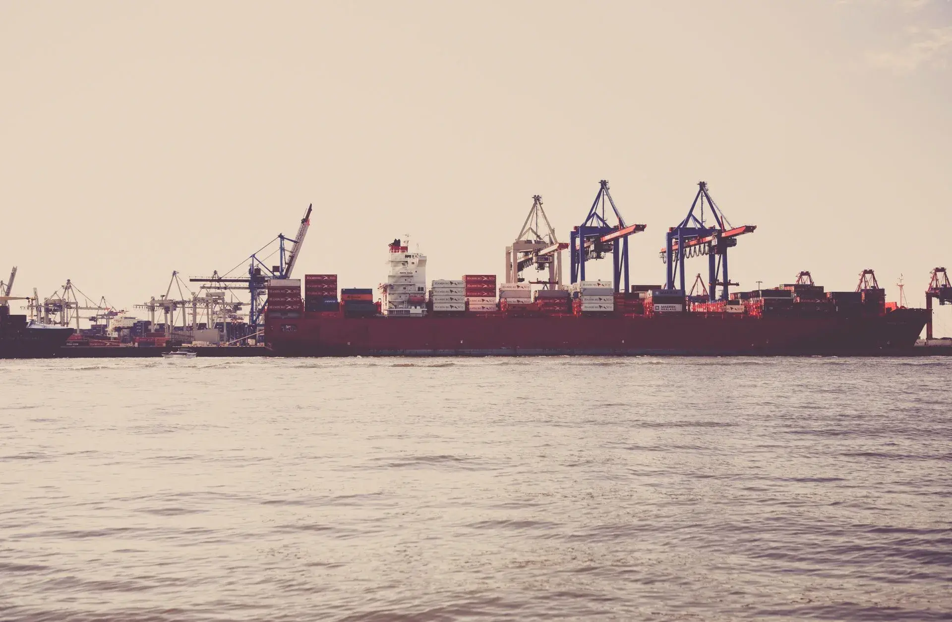 Container port at dusk with stacked shipping containers and gantry cranes
